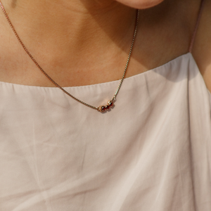 Necklace with small beads worn by a person against a neutral background